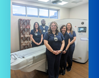 Radiology team posed infront of Xray machine and they are smiling.
